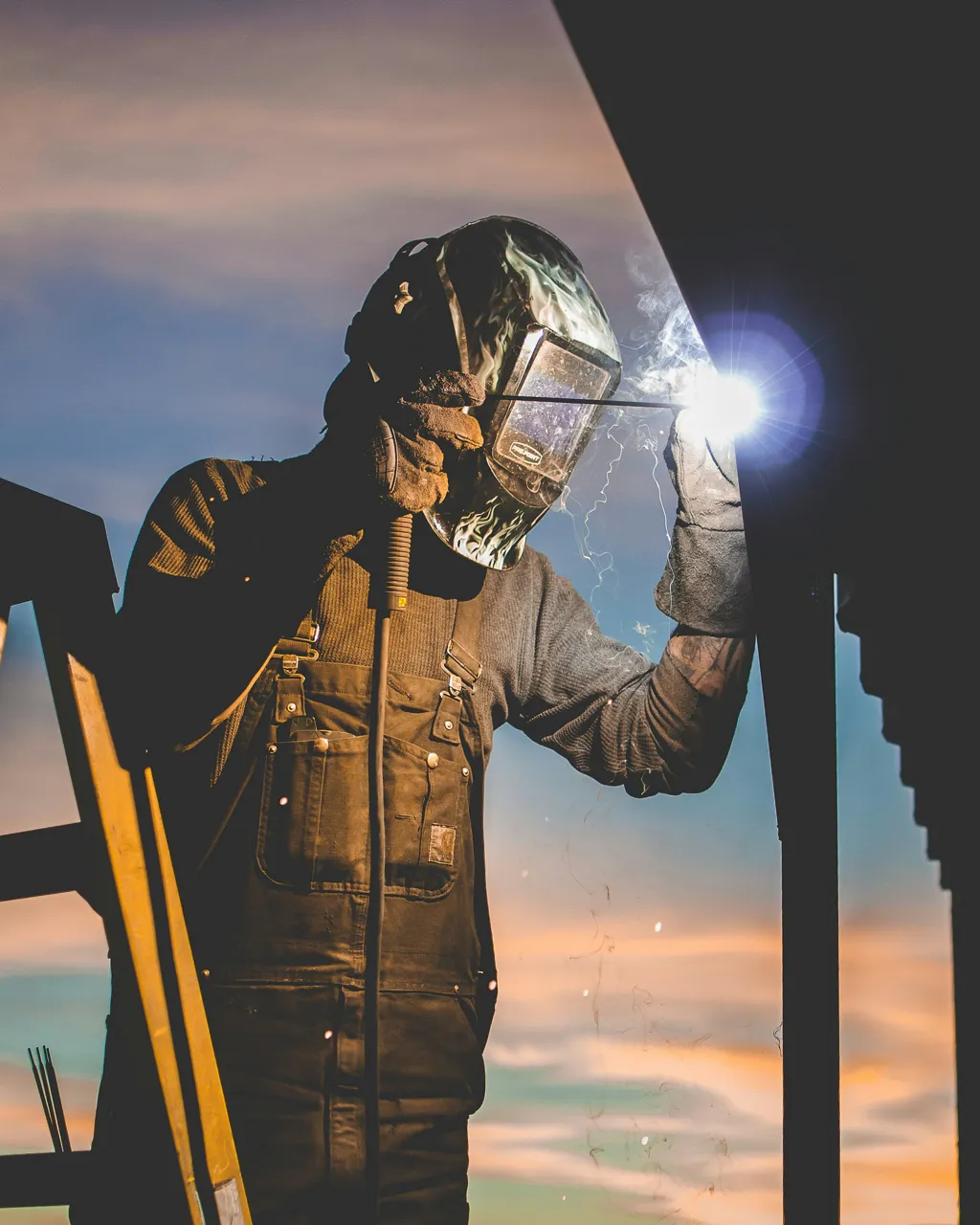 Welder in a protective hood laying a bead in the shop